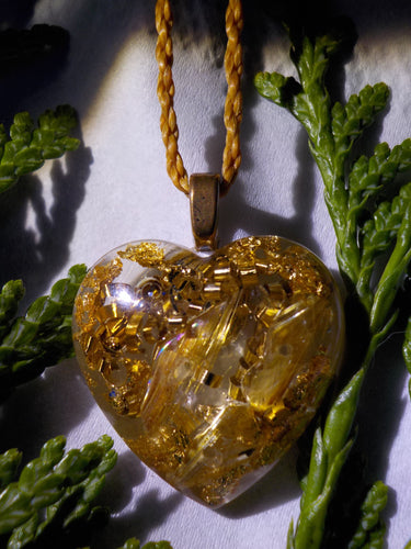 Orgonite en cristal de roche, quartz rutile, bronze et feuilles dorées.  2,3 cm.  Cordon polyester environ 95cm réglable par nœud macramé (offert).  Apporte calme, chaleur, harmonie et force vitale. Aide à vaincre la timidité en favorisant la franchise, la sincérité, la confiance en soi et l’indépendance.  Éloigne les énergies négatives et les personnes mal intentionnées. Aide pour une meilleure ouverture d’esprit. Protège du mauvais œil en cas de voyages astraux